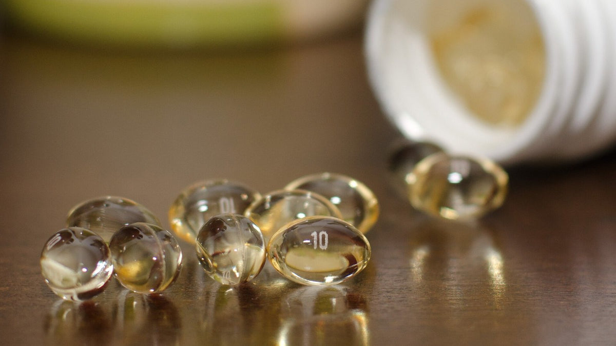 Clear softgel capsules beside an open supplement bottle